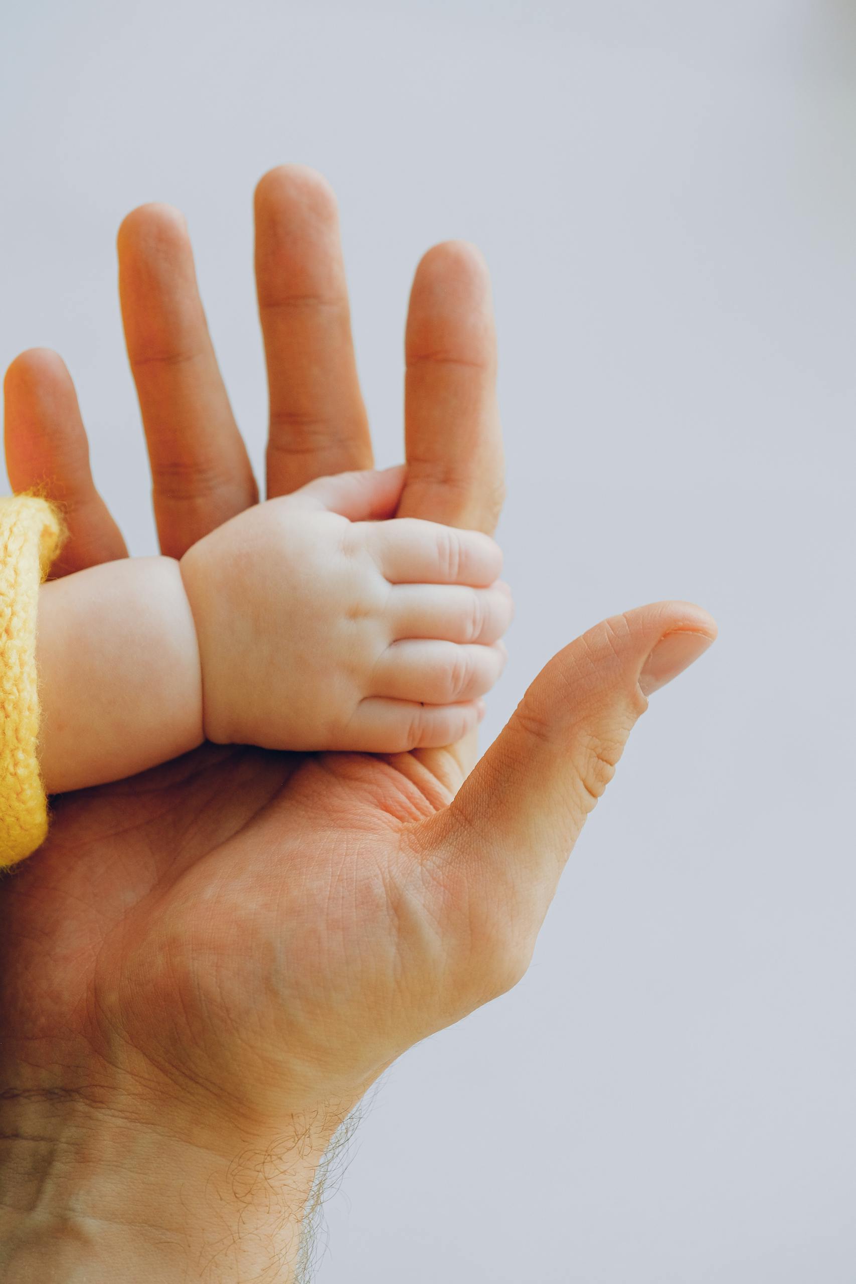 Tender moment captured between a baby and parent's hands symbolizing love and trust.